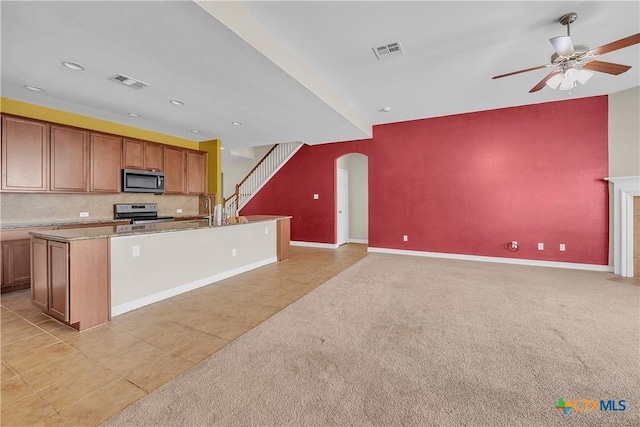 kitchen featuring a ceiling fan, visible vents, arched walkways, stainless steel appliances, and light carpet