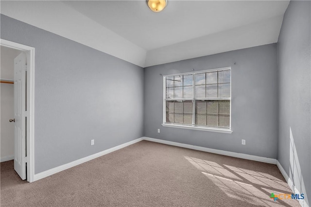 carpeted empty room with lofted ceiling and baseboards