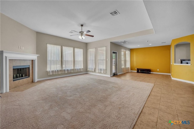 unfurnished living room with visible vents, baseboards, carpet, a tiled fireplace, and a ceiling fan