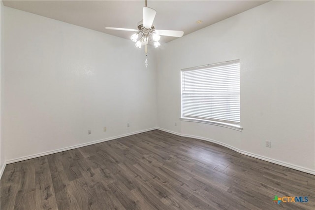 spare room featuring baseboards, dark wood finished floors, and a ceiling fan