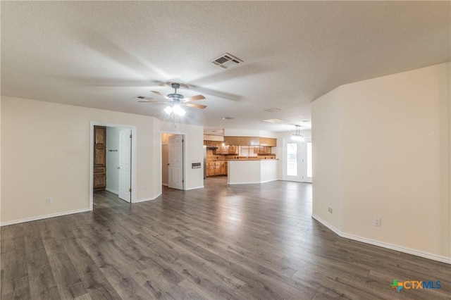 unfurnished living room with a textured ceiling, dark wood-style flooring, visible vents, baseboards, and a ceiling fan