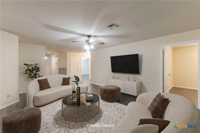 living area with baseboards, visible vents, and wood finished floors