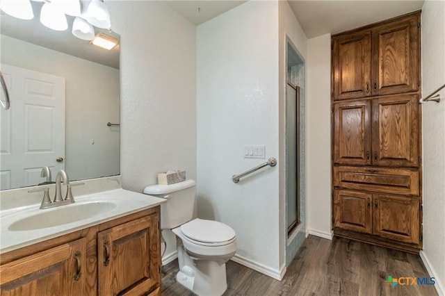 bathroom with a stall shower, baseboards, toilet, wood finished floors, and vanity