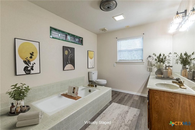 bathroom featuring a garden tub, vanity, toilet, and wood finished floors