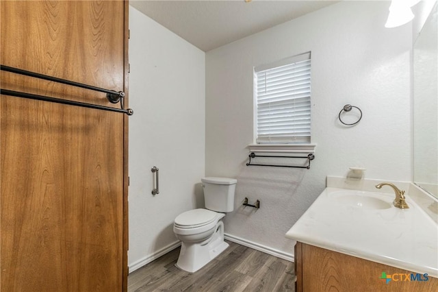 bathroom with baseboards, vanity, toilet, and wood finished floors