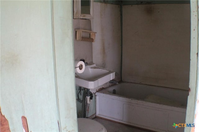 bathroom featuring a bath, toilet, and a sink