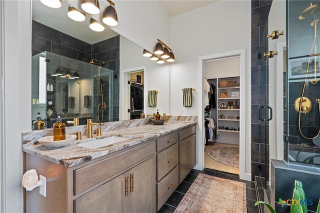 full bathroom featuring double vanity, a spacious closet, a shower stall, and a sink