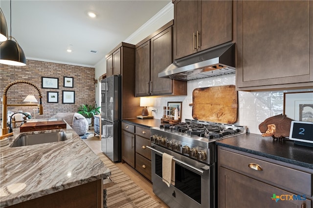 kitchen featuring dark brown cabinetry, high end stainless steel range oven, a sink, freestanding refrigerator, and under cabinet range hood