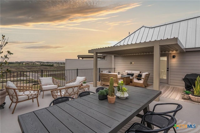 deck at dusk with outdoor dining area and an outdoor hangout area