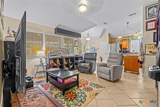 living room with a textured ceiling, ceiling fan, light tile patterned flooring, and lofted ceiling