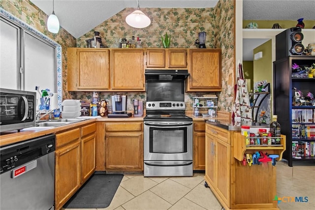 kitchen featuring pendant lighting, sink, range hood, light tile patterned flooring, and stainless steel appliances