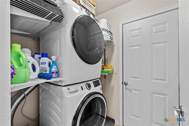 clothes washing area with stacked washer / dryer