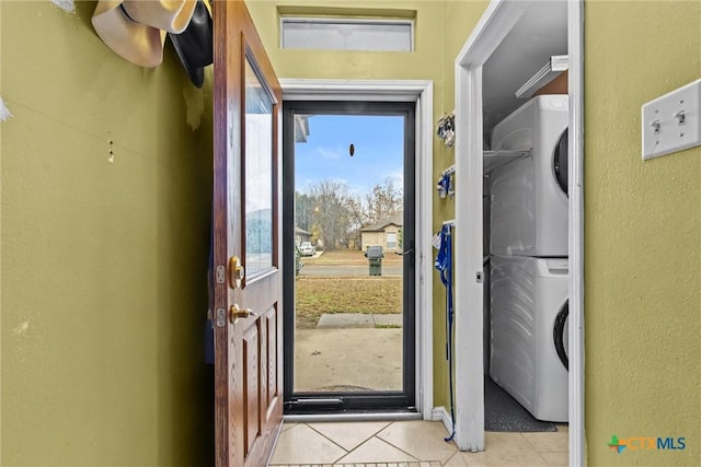 doorway featuring stacked washer / dryer and light tile patterned floors