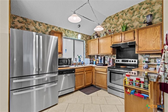 kitchen featuring stainless steel appliances, sink, decorative light fixtures, lofted ceiling, and light tile patterned flooring