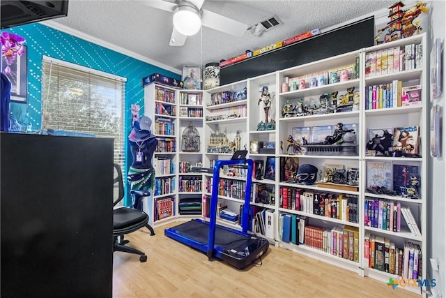 home office featuring ceiling fan, crown molding, wood-type flooring, and a textured ceiling