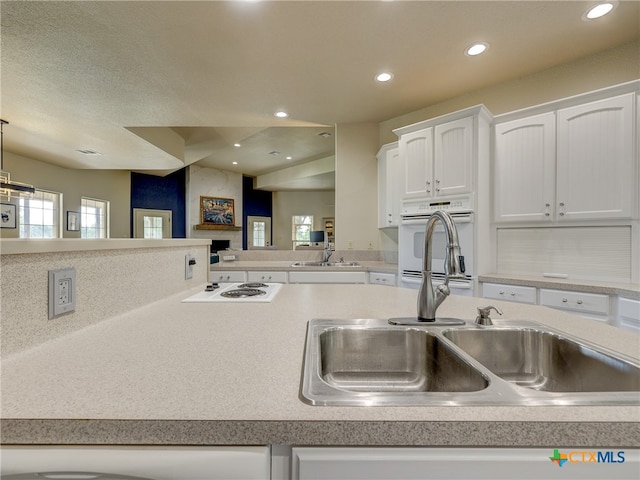 kitchen featuring white cooktop, white cabinetry, sink, and pendant lighting