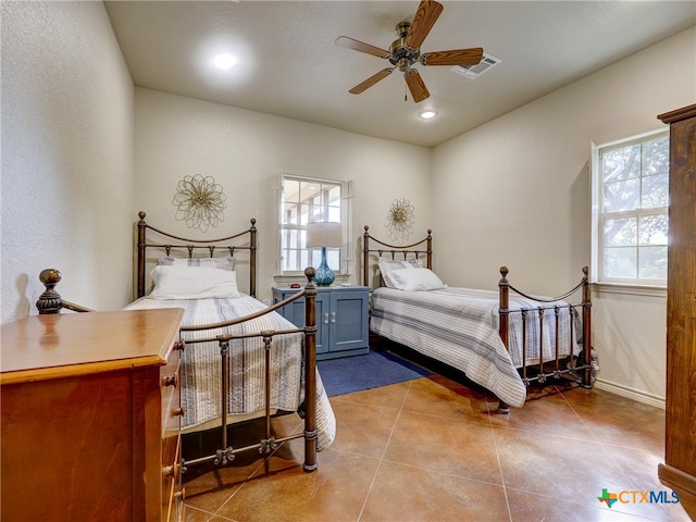 tiled bedroom featuring multiple windows and ceiling fan