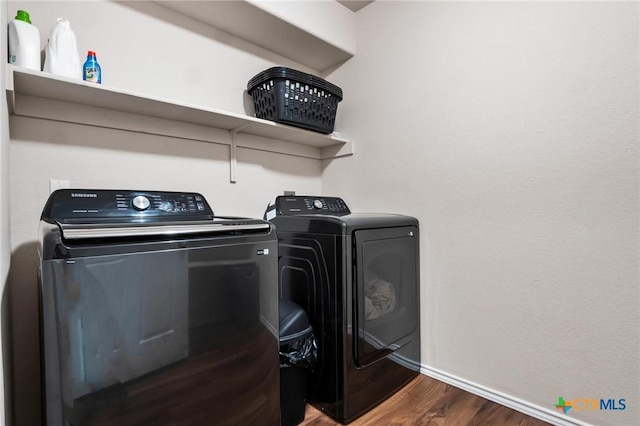 washroom with washing machine and clothes dryer, wood finished floors, and baseboards