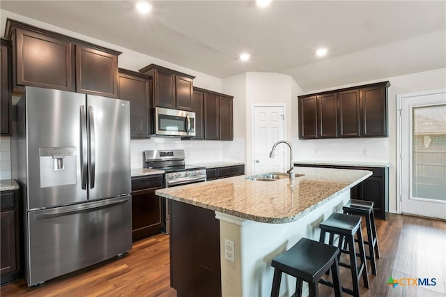 kitchen with appliances with stainless steel finishes, a sink, decorative backsplash, light stone countertops, and recessed lighting