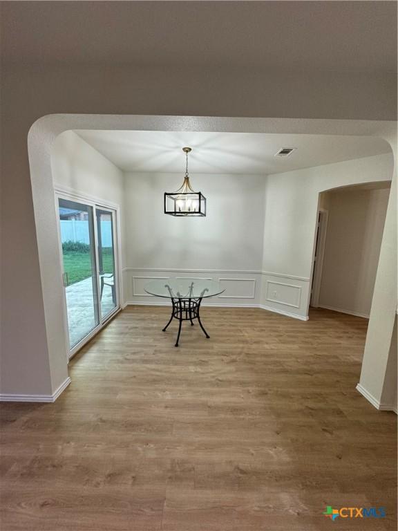 500 Chickasaw Dr, Harker Heights, TX 76548 - unfurnished dining area with arched walkways, a decorative wall, wood finished floors, and a wainscoted wall