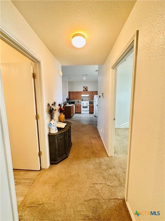 hallway featuring a textured ceiling and light colored carpet