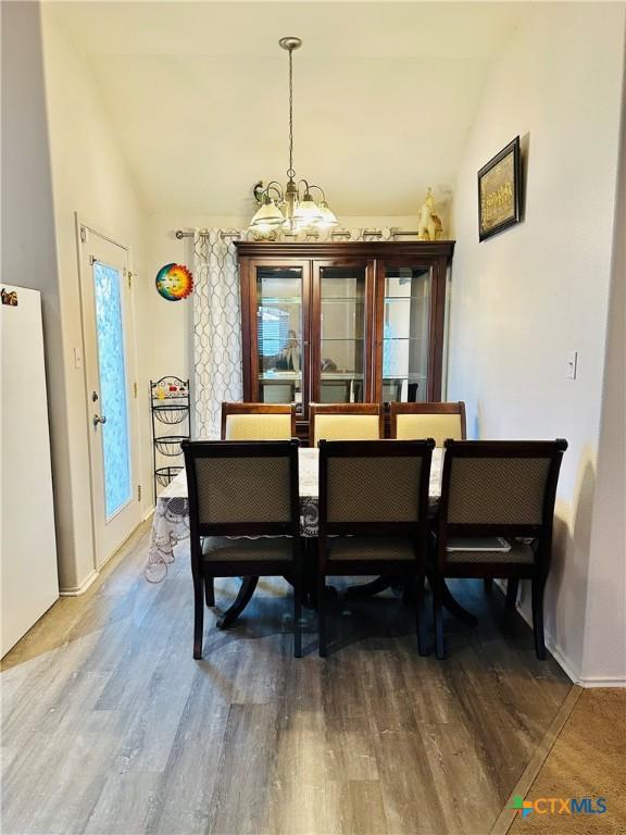 dining space with vaulted ceiling, a chandelier, and hardwood / wood-style floors