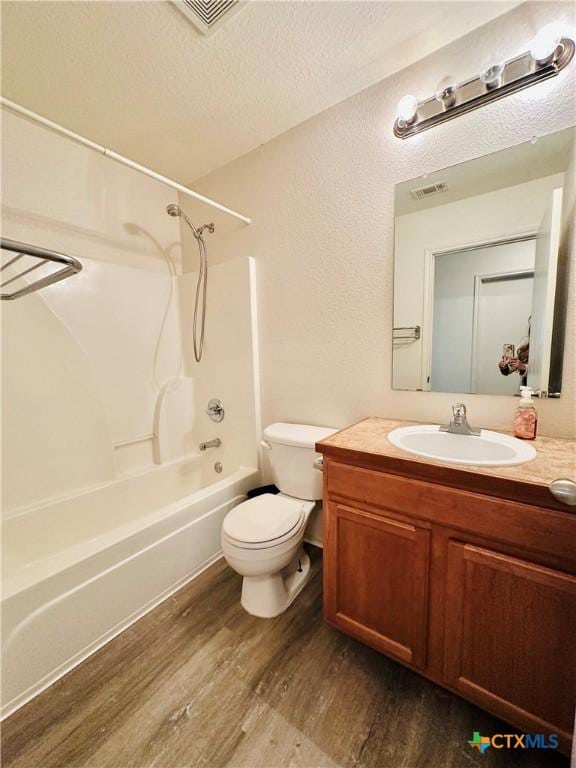 full bathroom with toilet, washtub / shower combination, wood-type flooring, a textured ceiling, and vanity