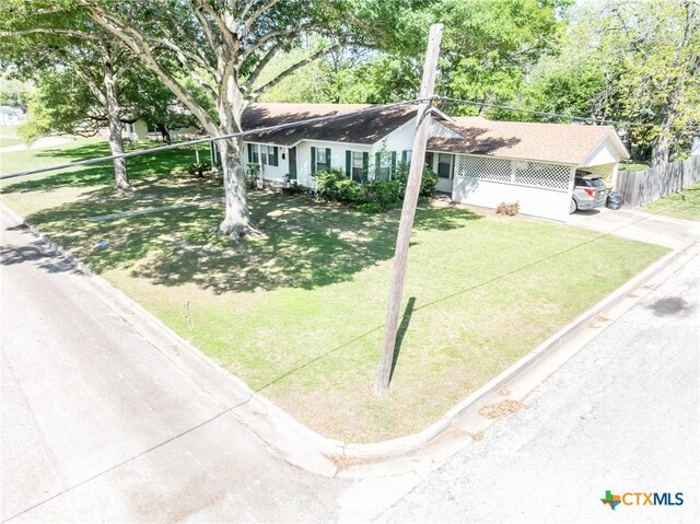 1429 Gardien St, Gonzales, TX 78629 - ranch-style home with a front yard, a carport, driveway, and fence