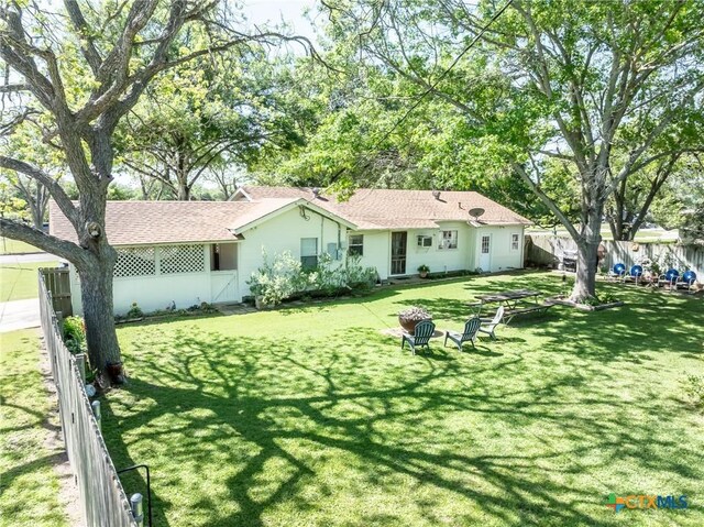 1429 Gardien St, Gonzales, TX 78629 - rear view of house featuring fence, a shingled roof, and a lawn