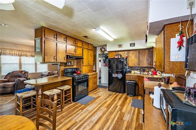 1429 Gardien St, Gonzales, TX 78629 - kitchen featuring black appliances, light countertops, brown cabinetry, and under cabinet range hood