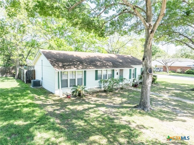 1429 Gardien St, Gonzales, TX 78629 - view of front of home with fence, a shingled roof, a front yard, and central air condition unit