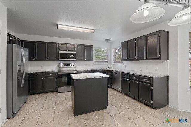 4401 Maggie Dr, Killeen, TX 76549 - kitchen featuring stainless steel appliances, light stone countertops, a center island, and dark cabinetry