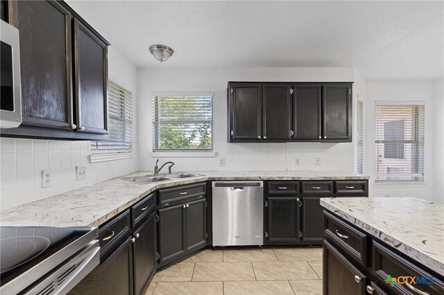 4401 Maggie Dr, Killeen, TX 76549 - kitchen with stainless steel dishwasher, light tile patterned floors, decorative backsplash, a sink, and light stone countertops
