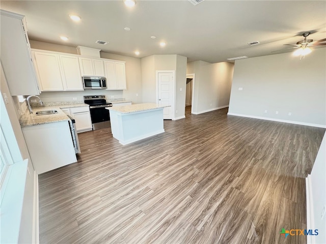 kitchen with sink, hardwood / wood-style flooring, white cabinetry, stainless steel appliances, and a center island