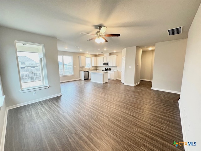 unfurnished living room featuring a textured ceiling, dark hardwood / wood-style floors, and ceiling fan