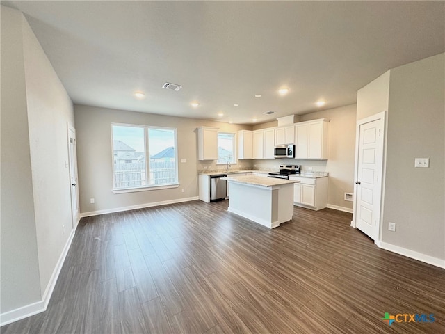 kitchen featuring white cabinetry, dark wood-type flooring, a center island, and appliances with stainless steel finishes