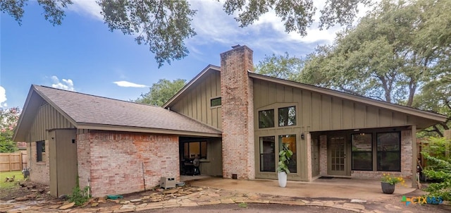 105 Creekside Dr, Victoria, TX 77904 - back of property with a chimney, a patio area, brick siding, board and batten siding, and roof with shingles