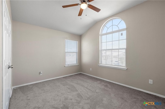 empty room featuring lofted ceiling, carpet, baseboards, and ceiling fan