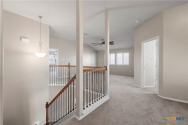 hall featuring carpet floors, baseboards, and an upstairs landing