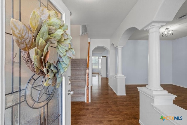 entryway with arched walkways, stairway, wood finished floors, and decorative columns