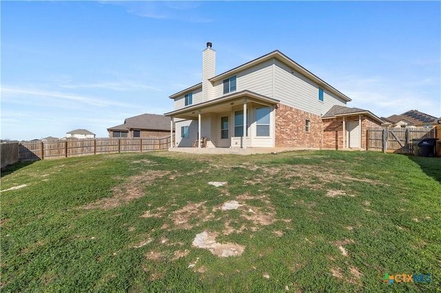 back of property with brick siding, a chimney, a fenced backyard, and a lawn