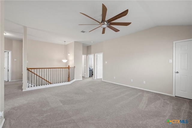 spare room featuring ceiling fan, visible vents, baseboards, vaulted ceiling, and carpet