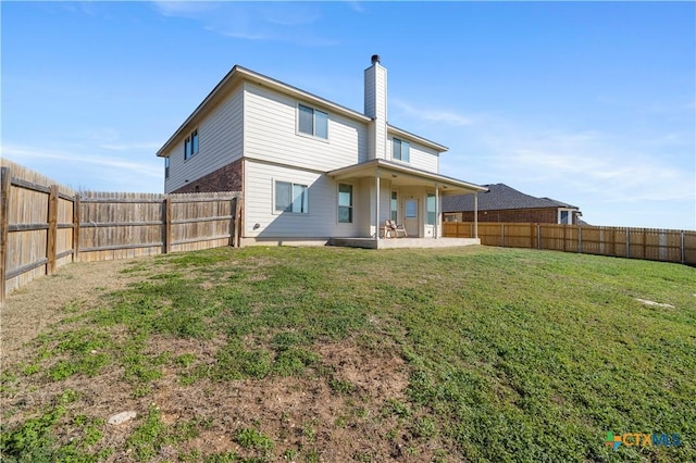 back of house featuring a yard, a chimney, a patio area, and a fenced backyard