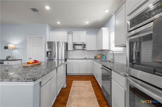 kitchen with stone counters, visible vents, appliances with stainless steel finishes, and a sink