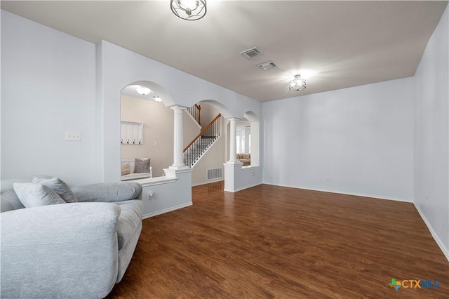 living room with visible vents, decorative columns, arched walkways, and wood finished floors