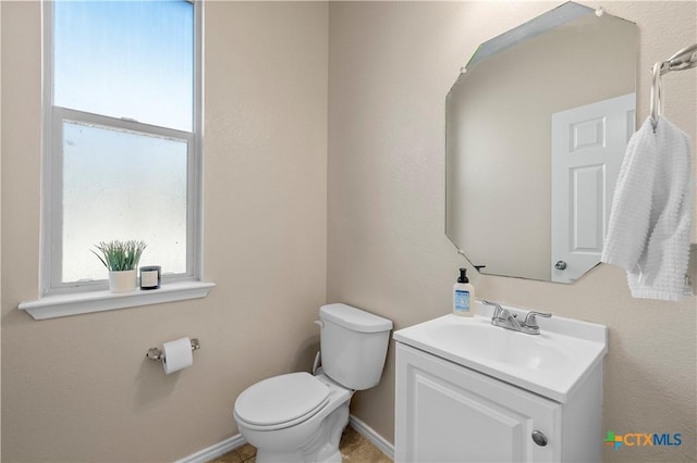 bathroom with toilet, baseboards, and vanity