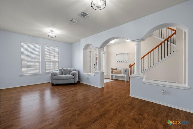 unfurnished room with decorative columns, visible vents, arched walkways, and wood finished floors