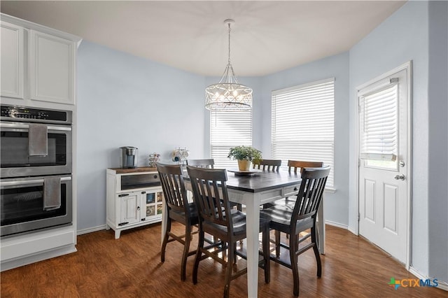 dining space with dark wood-style floors, a chandelier, and baseboards