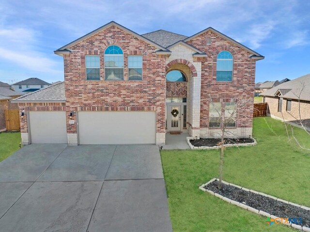 traditional-style home with concrete driveway, a front yard, and brick siding