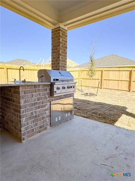 view of patio / terrace featuring a sink, area for grilling, a fenced backyard, and exterior kitchen